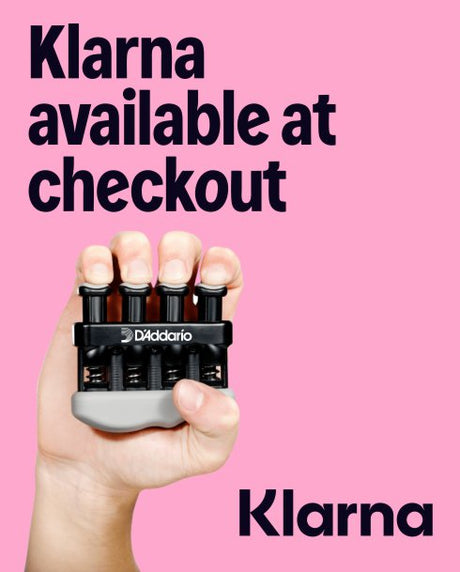 Hand holding a D'Addario exerciser with 'Klarna available at checkout' text on a pink background