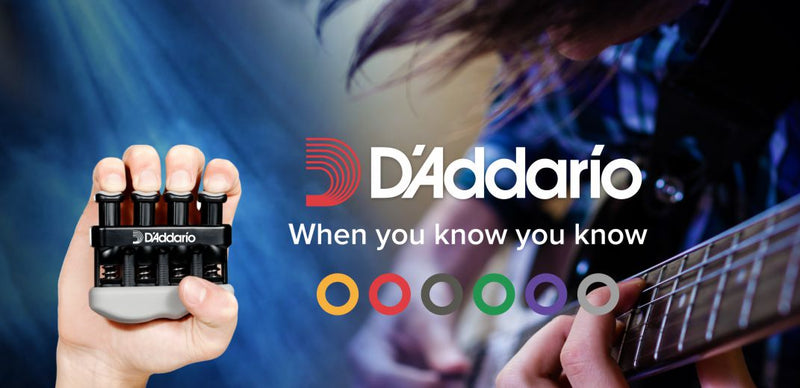 Person holding a D'Addario guitar string set with a blurred background of playing guitar, featuring D'Addario branding.